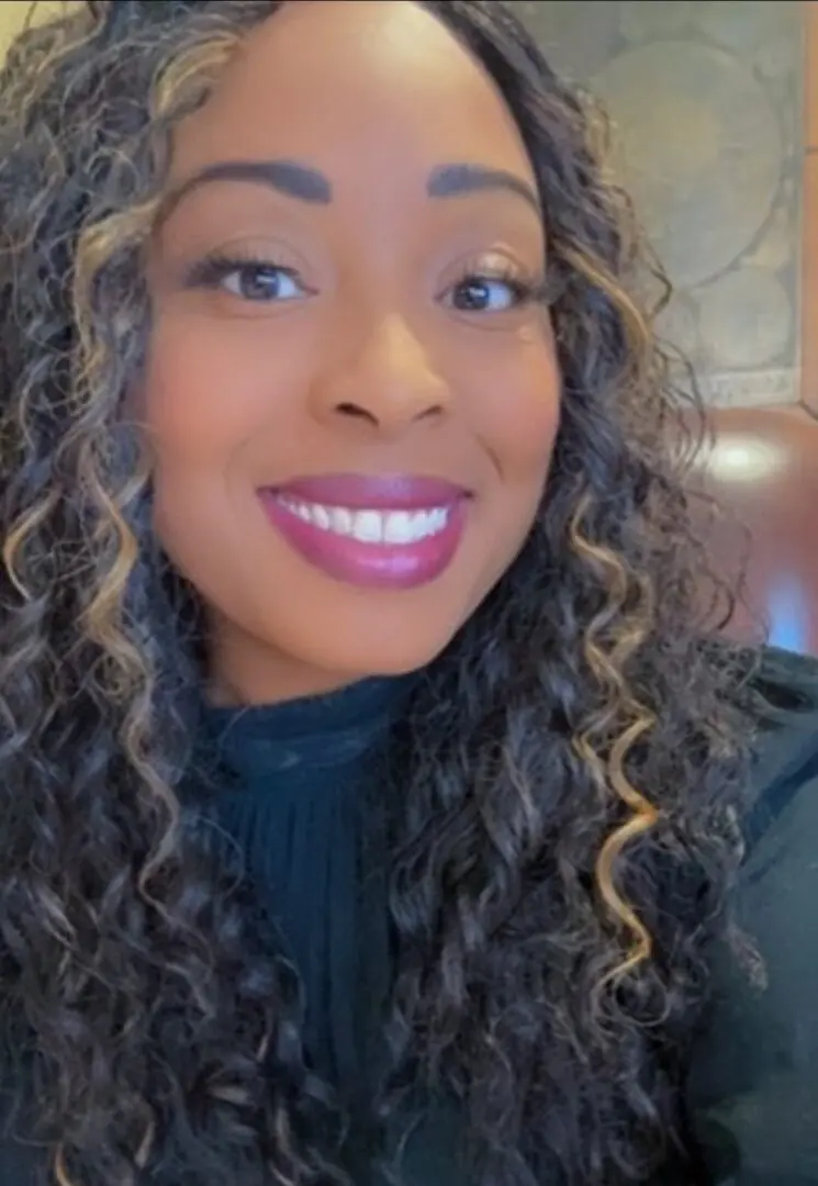 A woman with long curly hair smiles for the camera.